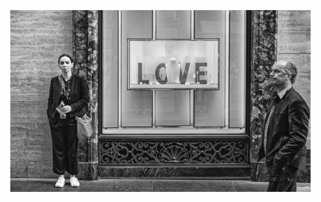 Love (passing ships) print, 148.5 x 90 cm with white border — two strangers passing a LOVE jewellery window display, Via dei Condotti, Rome, black and white street photography by Tom Parsons