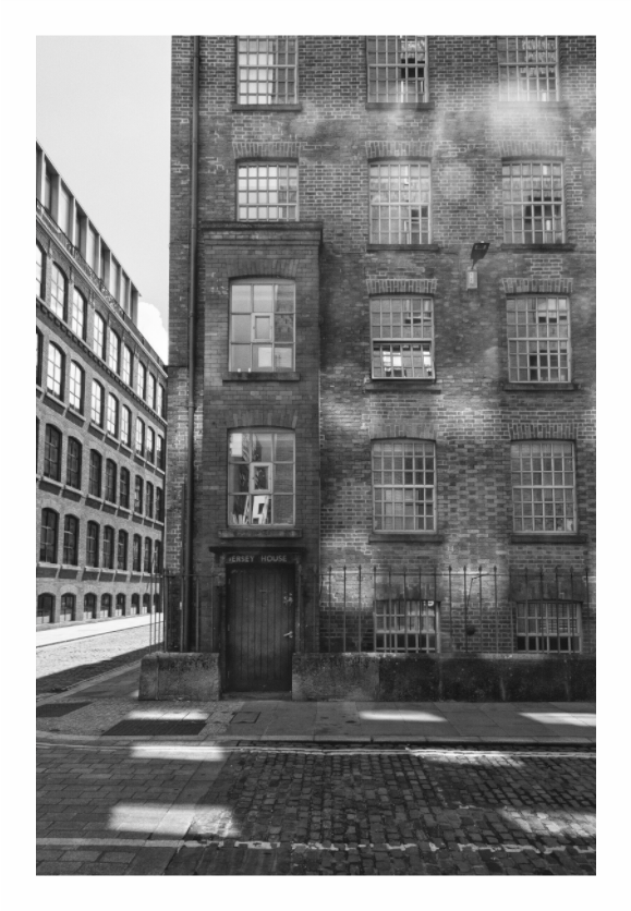 Cobbled Street in Manchester print, 80 × 120 cm with white border — cobbled side street between Victorian brick warehouse buildings, Manchester, black and white street photography by Tom Parsons
