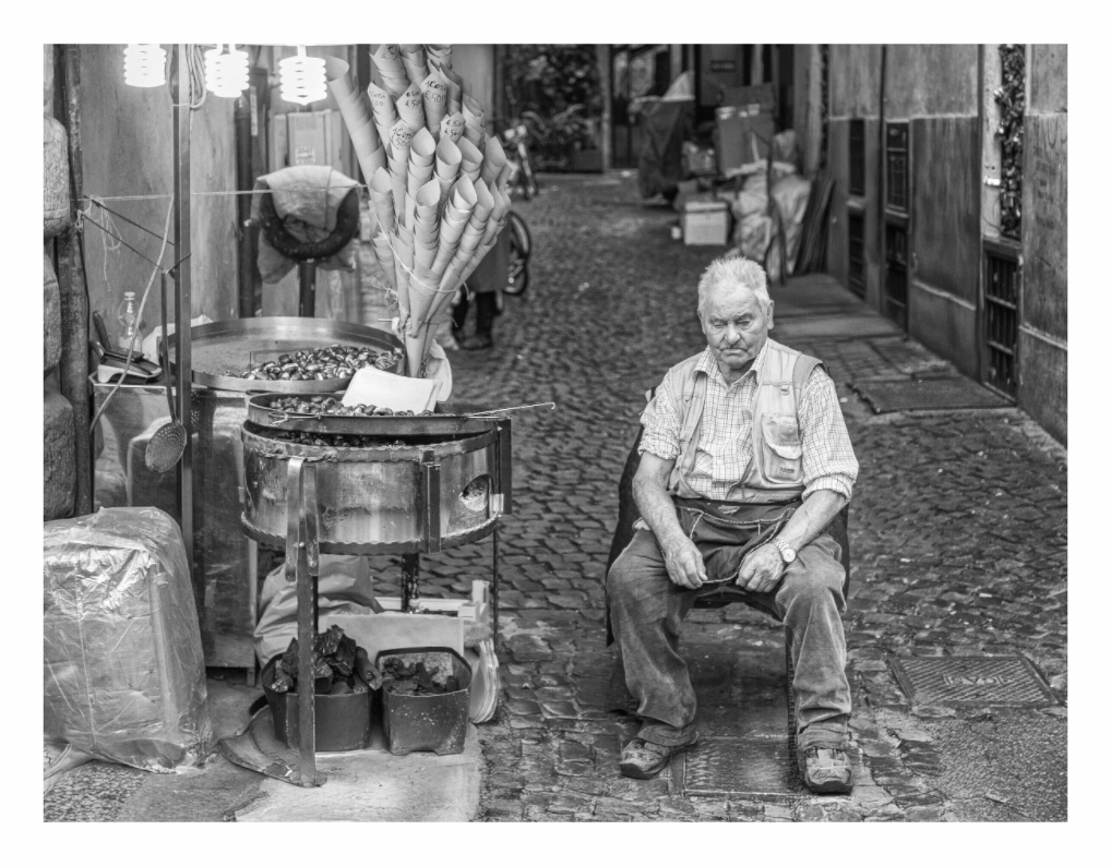 Hot Chestnut Vendor print, 118.4 x 90 cm with white border — elderly street vendor beside his chestnut roasting cart near the Spanish Steps, Rome, black and white portrait photography by Tom Parsons