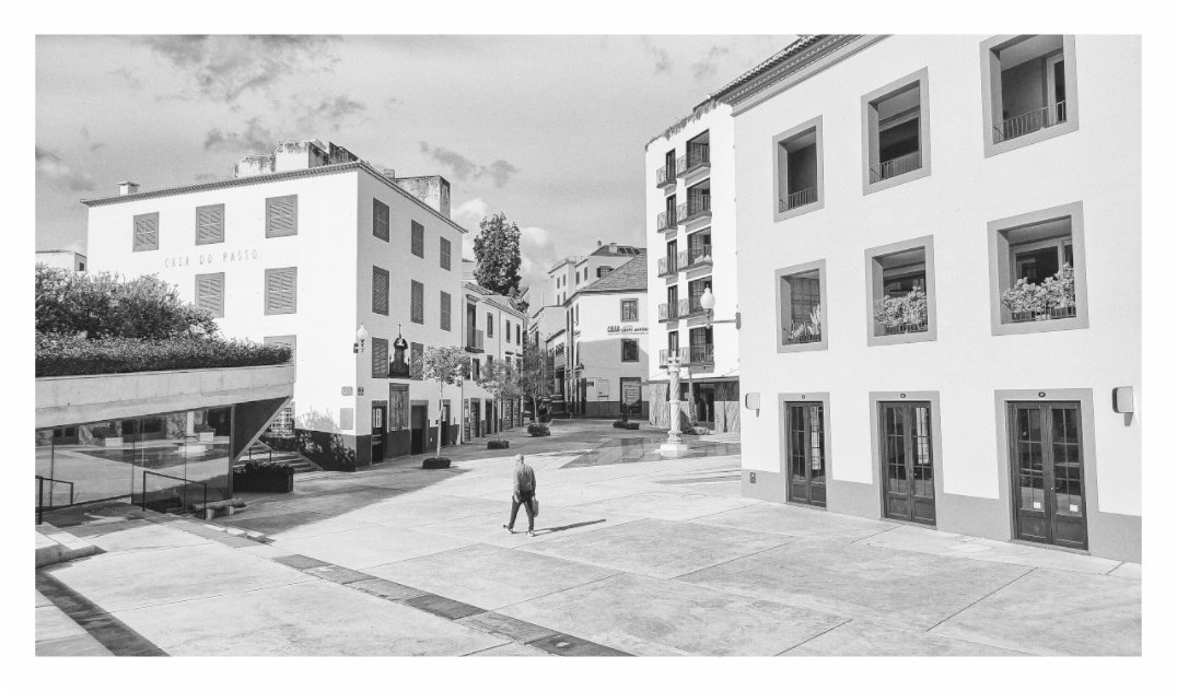 Man in Square print, 160 × 90 cm with white border — a lone man crossing a town piazza, Madeira, Portugal, black and white street photography by Tom Parsons