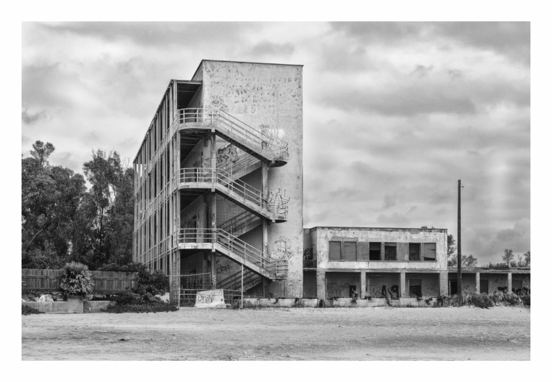 Abandoned print, 120 × 80 cm with white border — ruined concrete apartment block on the beach under a stormy sky, Lazio, Italy, black and white architecture photography by Tom Parsons