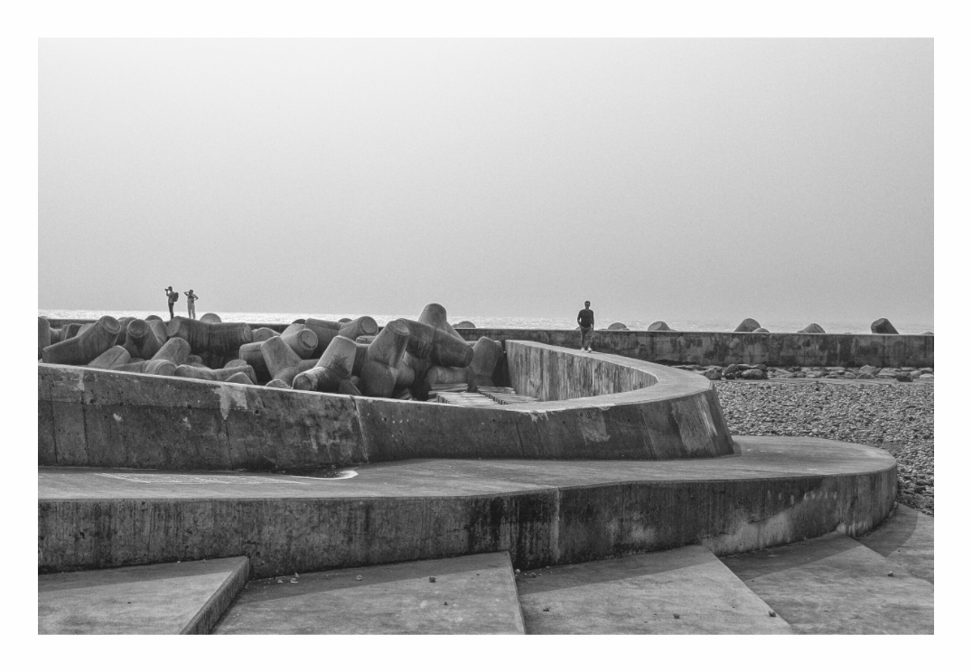 Steps print, 120 × 80 cm with white border — curved concrete steps and sea defences leading to the beach, figures for scale, Madeira, black and white architecture photography by Tom Parsons