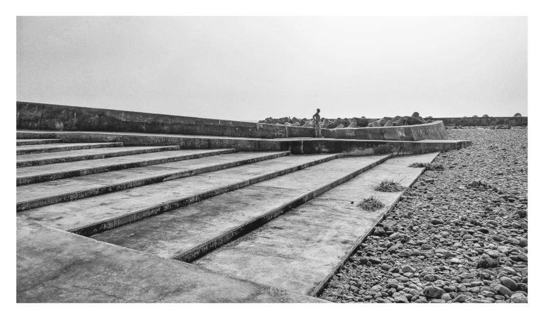 Lone man on steps print, 160 × 90 cm with white border — a lone man standing on concrete beach steps, Madeira, black and white landscape photography by Tom Parsons
