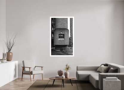 The Barbican print, 90 × 154.8 cm on Hahnemühle FineArt Pearl — a cylindrical concrete stair tower rising between residential blocks, London, black and white architectural photography by Tom Parsons